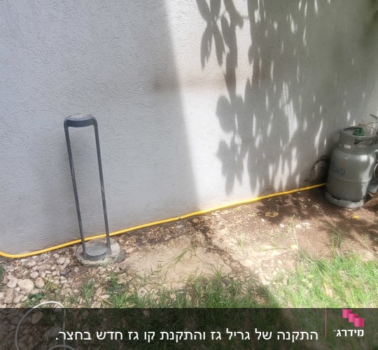 צינור גז צהוב מחובר למיכלי גז ליד קיר חיצוני